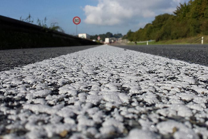 Makro-Ansicht einer Agglomeratmarkierung. Man kann gut erkennen, wie dick die Farbe auf dem Asphalt aufgebracht ist.