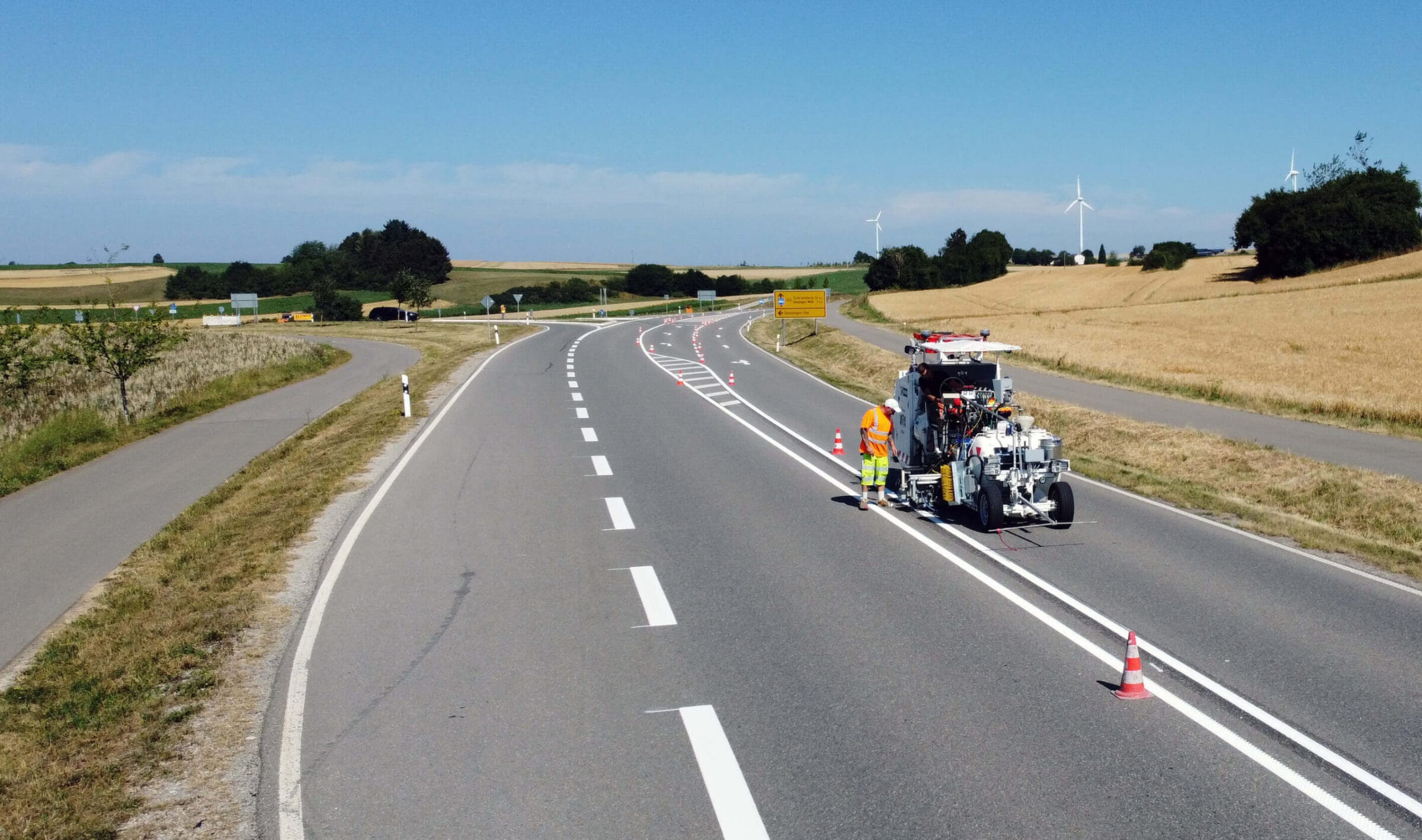 Markierungsfahrzeug bringt frische Markierung auf einer Landstraße auf.